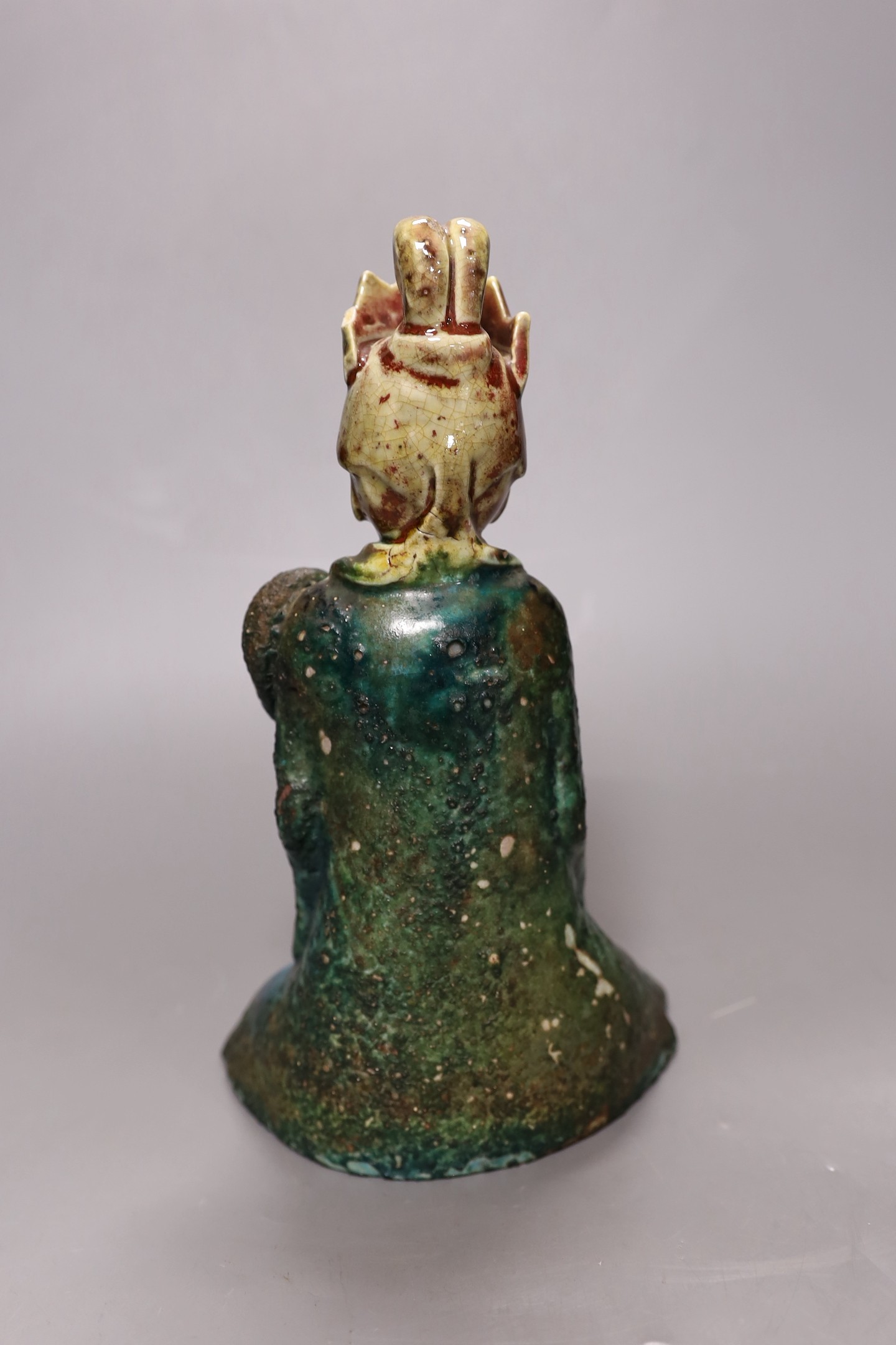 A 19th century Chinese flambé glazed seated figure of an immortal, 25cm